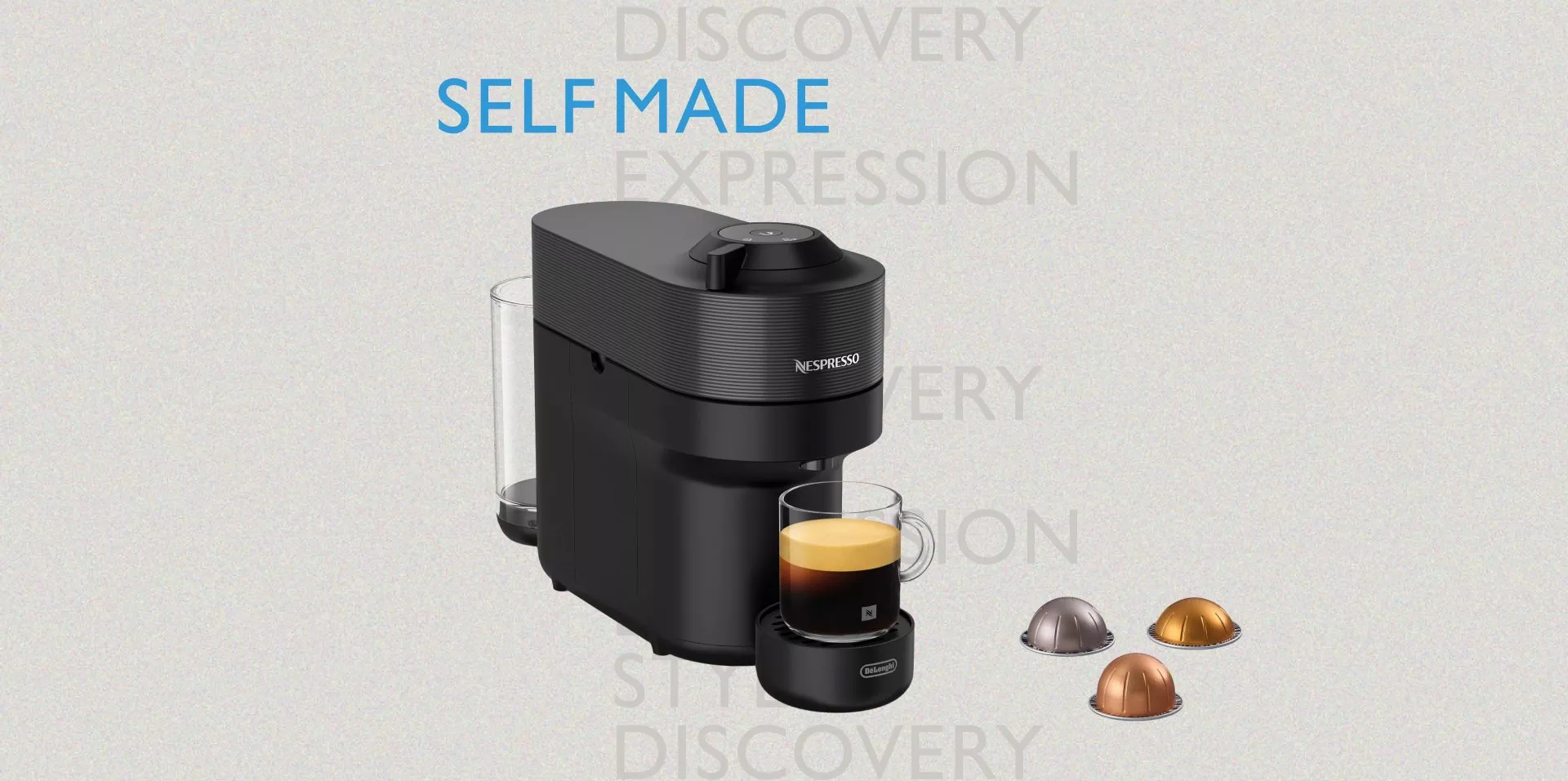 A black Nespresso Vertuo Pop coffee machine with a clear water tank. A glass mug filled with coffee sits on the drip tray, and three espresso capsules are positioned to the right. The text "SELF MADE" in blue is visible above the machine.