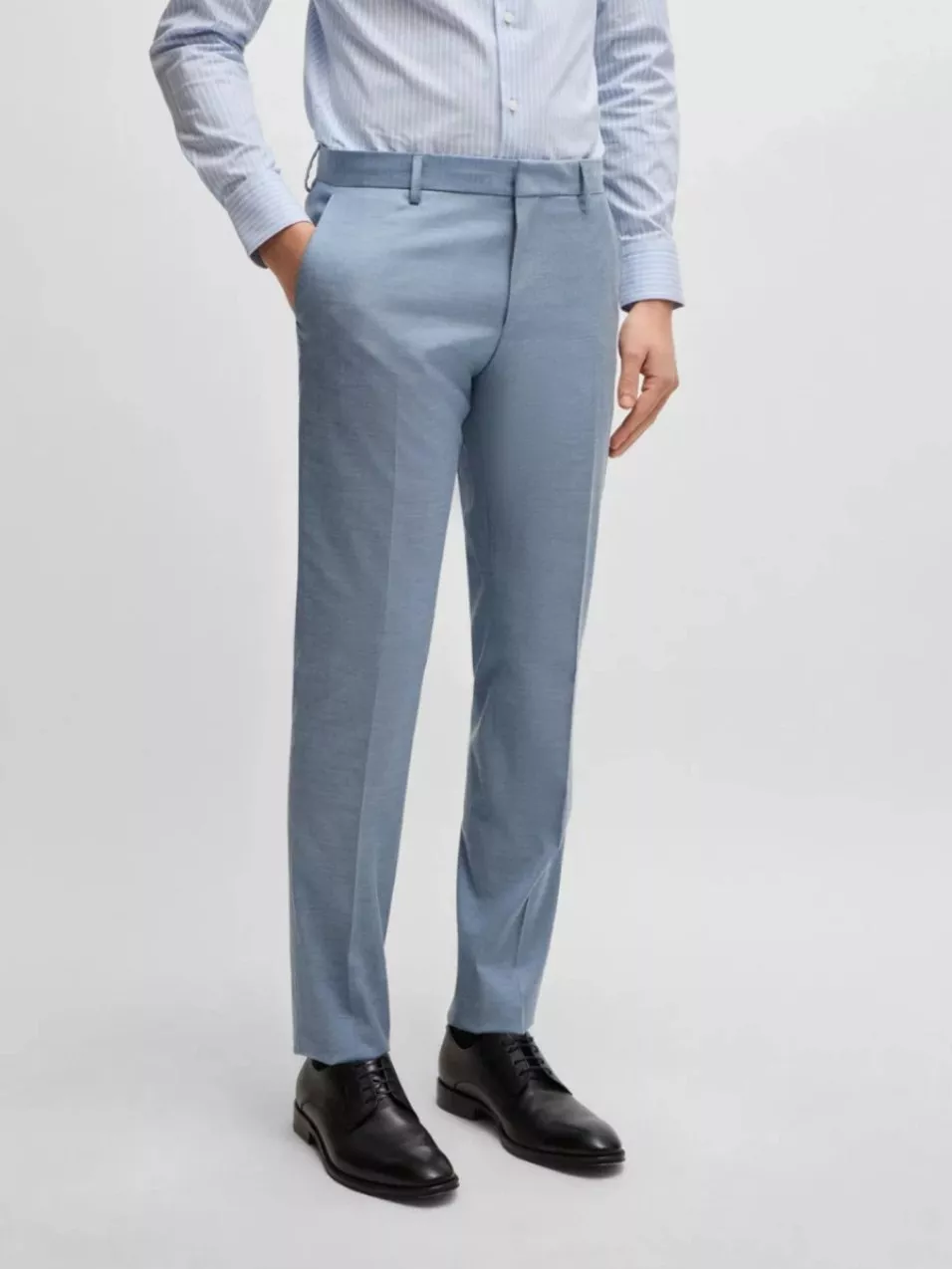 Man wearing slim fit light blue formal trousers with crease front, styled with striped shirt and black leather dress shoes