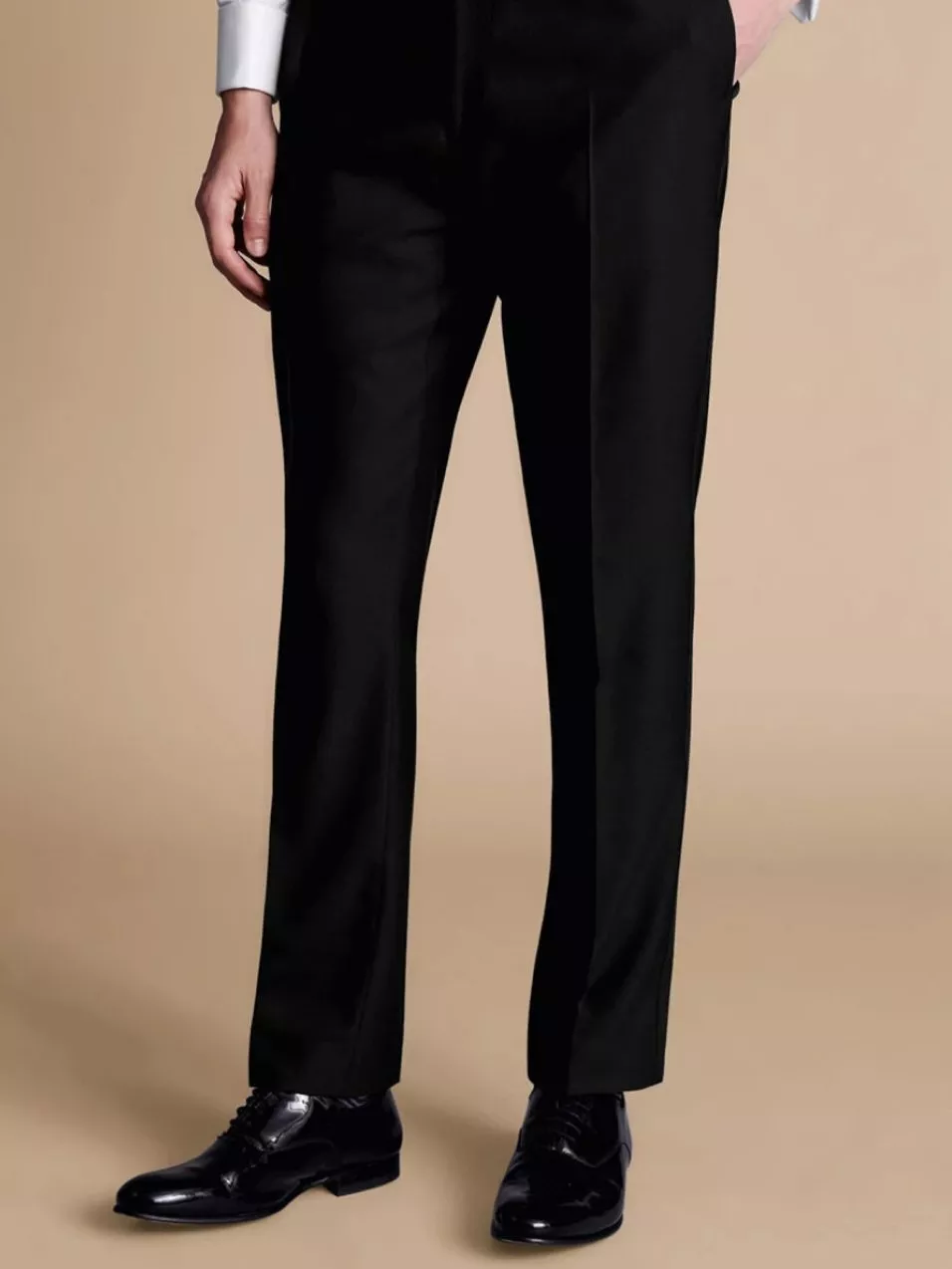 Man wearing tailored black trousers and polished black shoes, paired with a crisp white shirt.