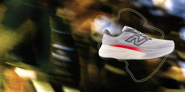 A side profile of a light grey New Balance running shoe featuring a dark blue 'N' logo and a thick, white foam midsole with a vibrant red streak.