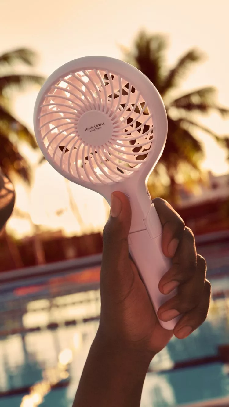 someone holding a fan up to there face