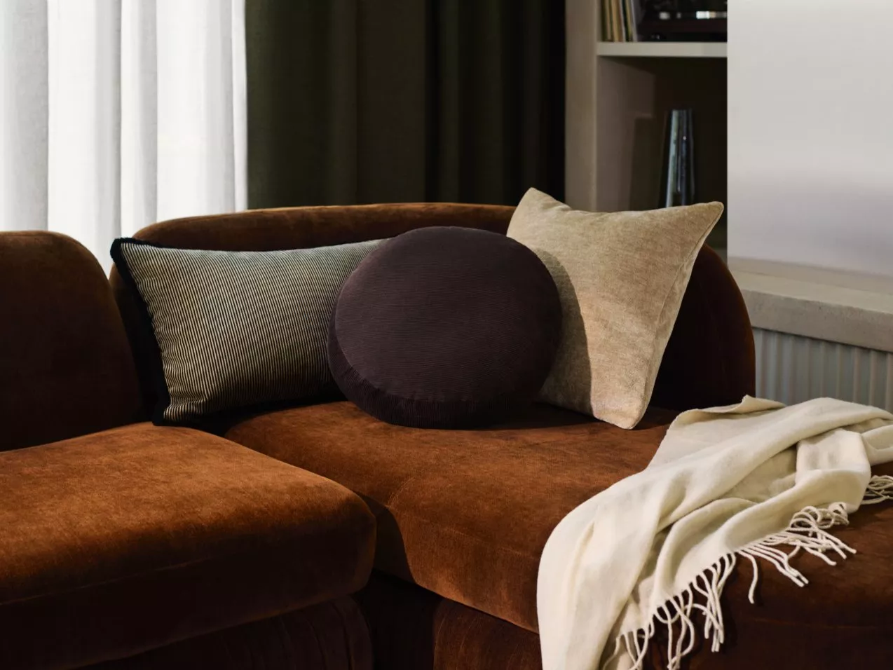 Burnt orange sofa with scatter cushions and blanket