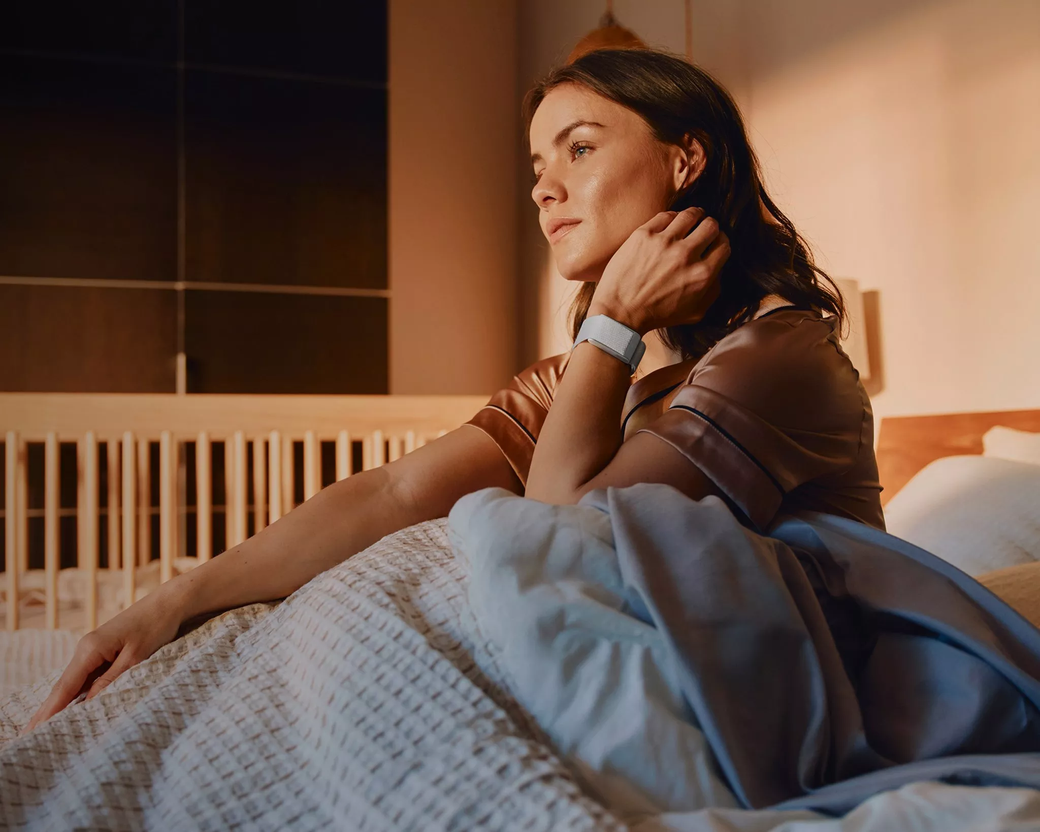 Women wearing a WHOOP tracker device sitting in a bed