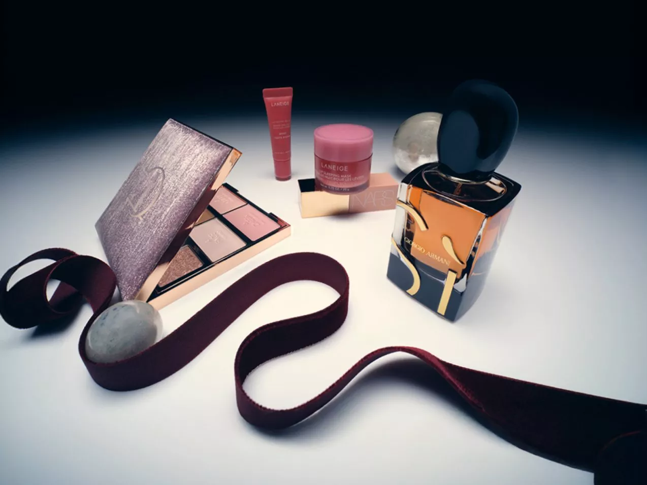 Image of make-up on a white table with a red ribbon around it