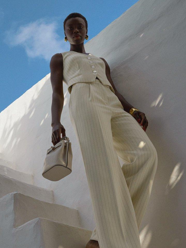 Female model in a white co-ord outfit posing on the stairs