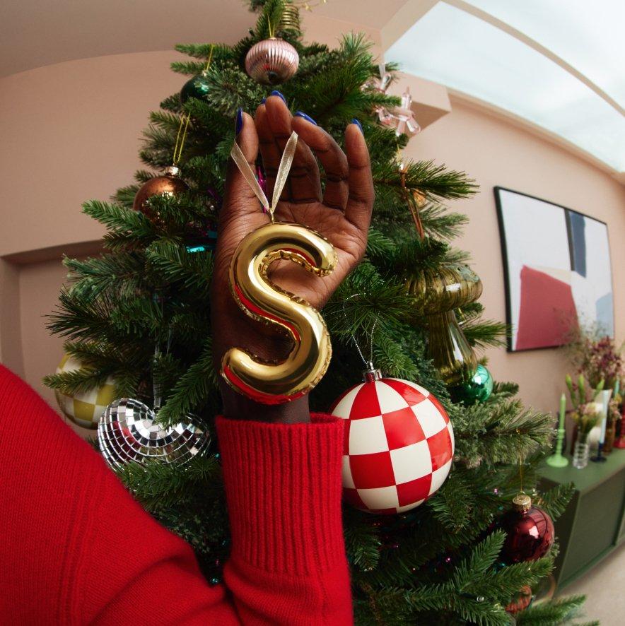 Person holding a Christmas bauble infront of a Christmas tree