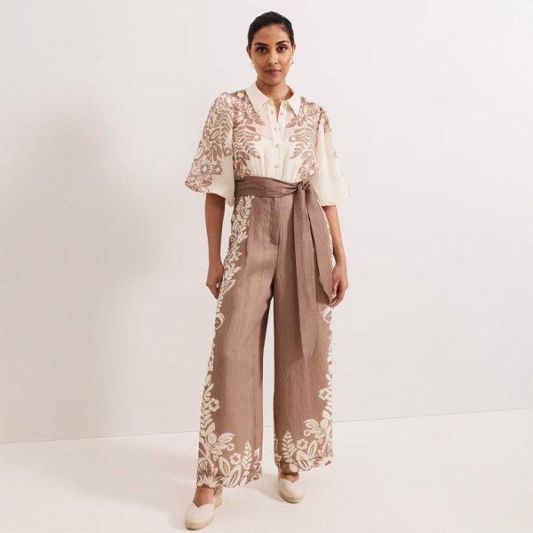 Woman in embroidered jumpsuit with a wide belt.