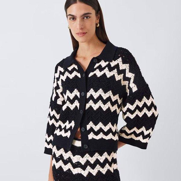 Woman wearing a black and white zigzag-patterned knitted cardigan and matching skirt set.