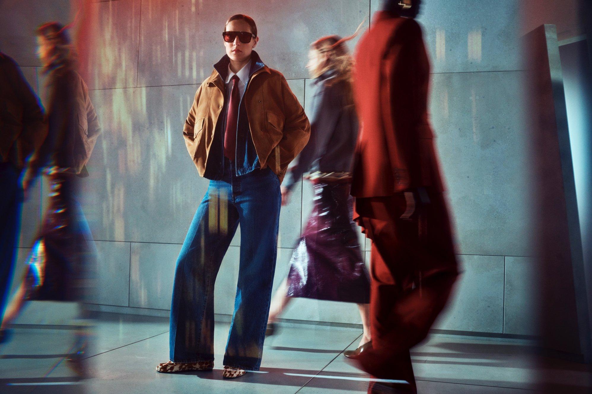 women dressed in smart outfit and sunglasses with other blurry people walking behind