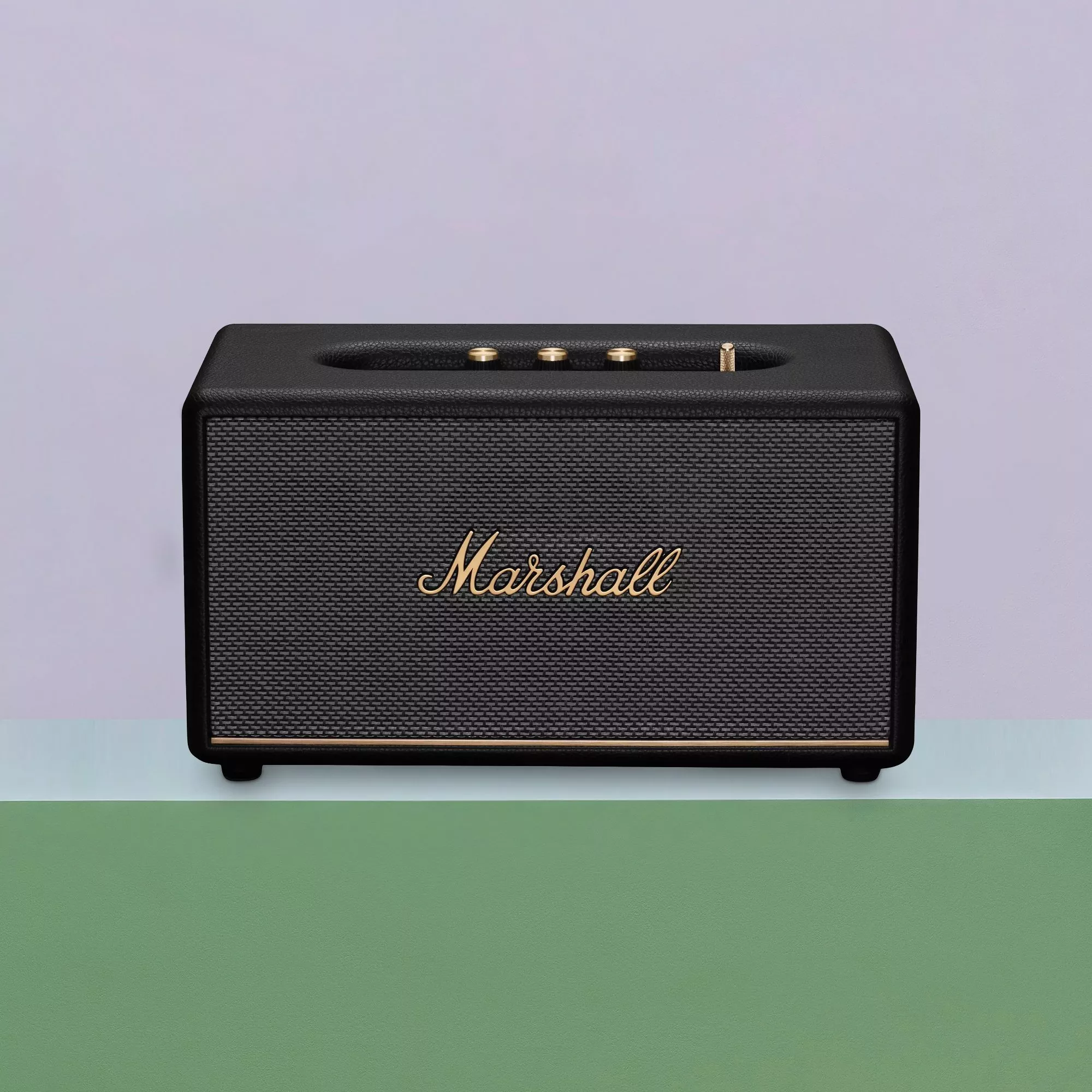 Black Marshall Bluetooth speaker with gold controls and logo, front view on pastel background, product photo