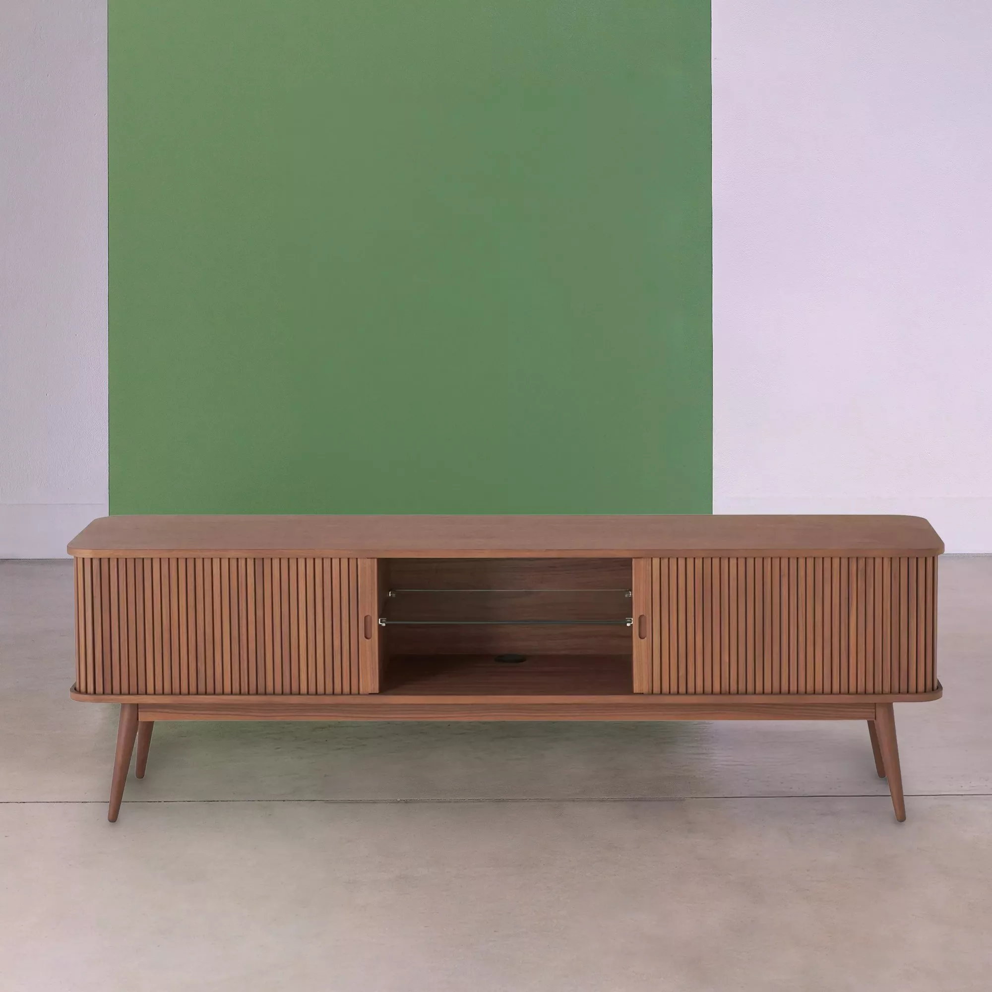 Mid-century modern wooden TV stand with slatted doors and open shelf, set against a green and white wall