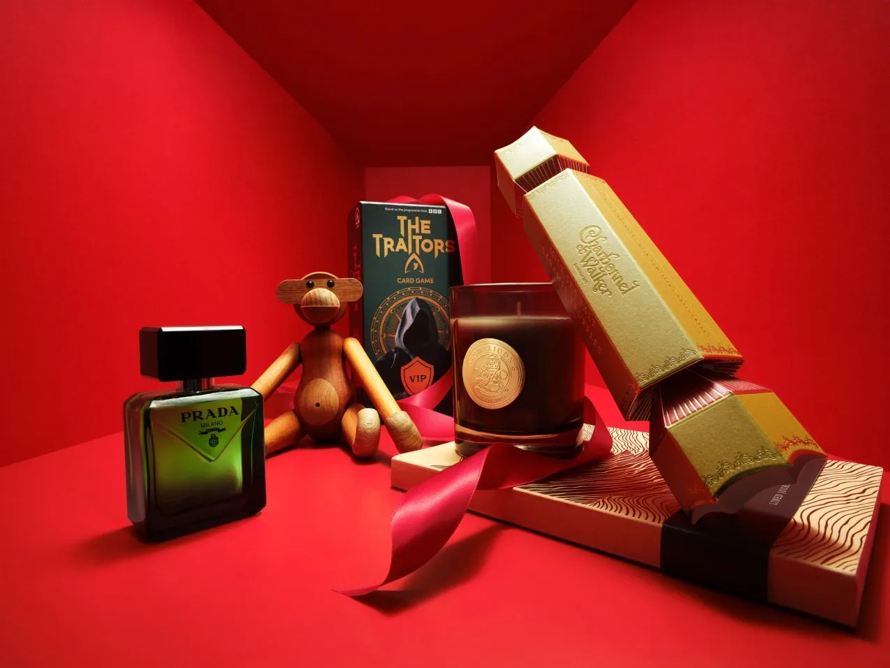 Luxury gift hamper with fragrance, candle, card game and cracker packaging on a red festive background