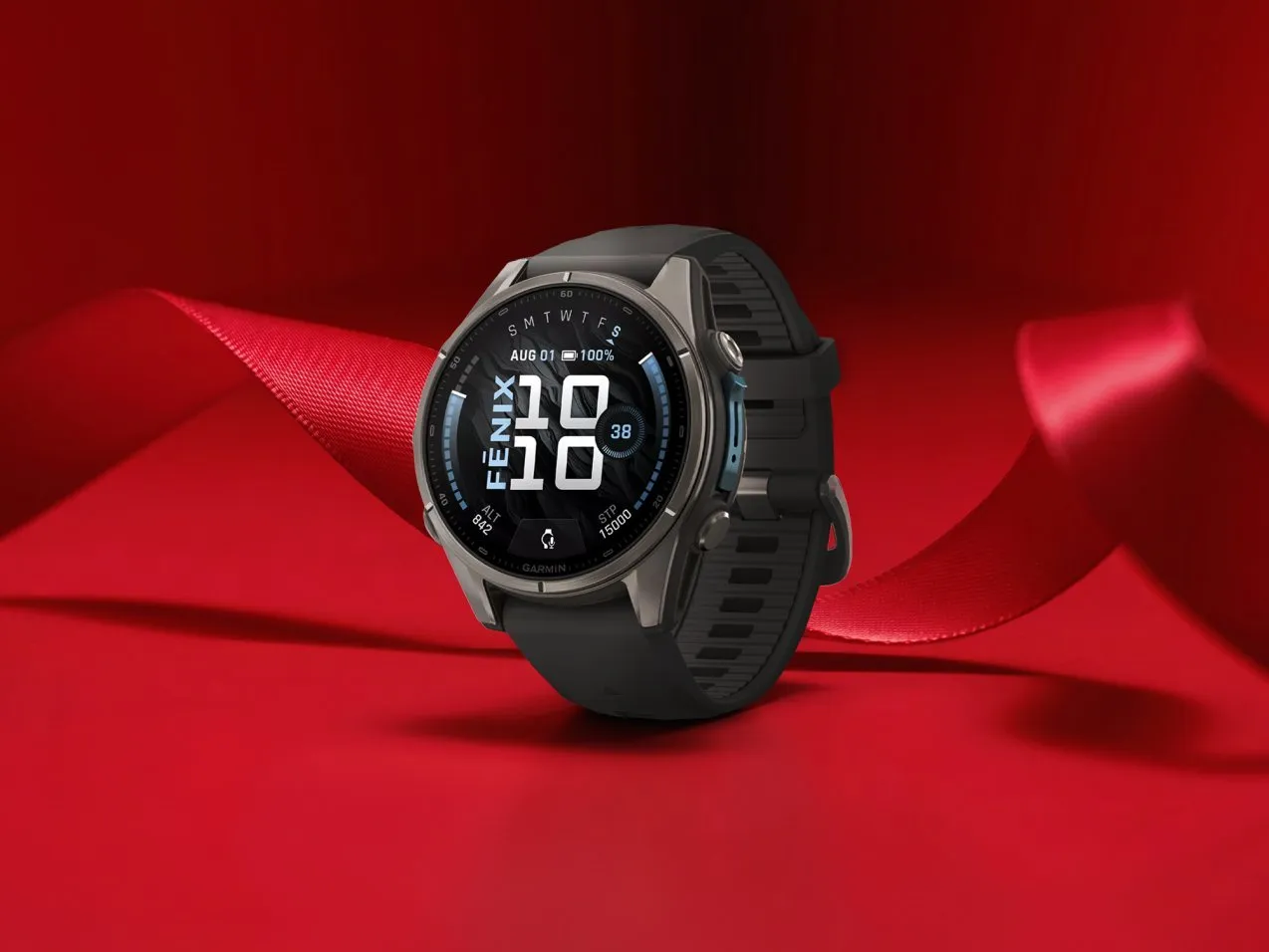 Garmin Fenix multisport GPS smartwatch with black strap on red gift wrap and ribbon background, close-up product shot