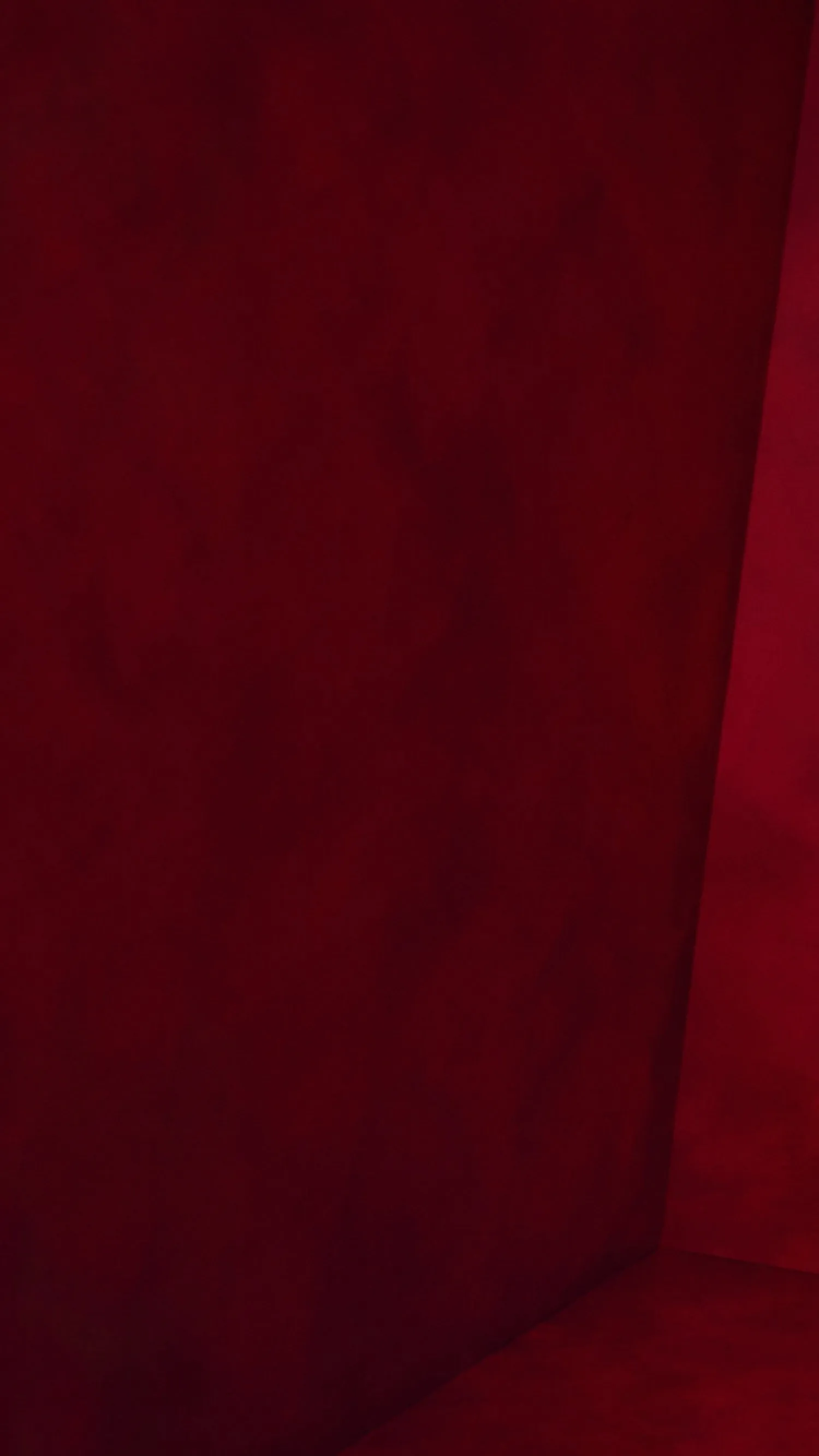 Deep red fabric texture background with soft folds and shadows, ideal for luxury upholstery or textile design