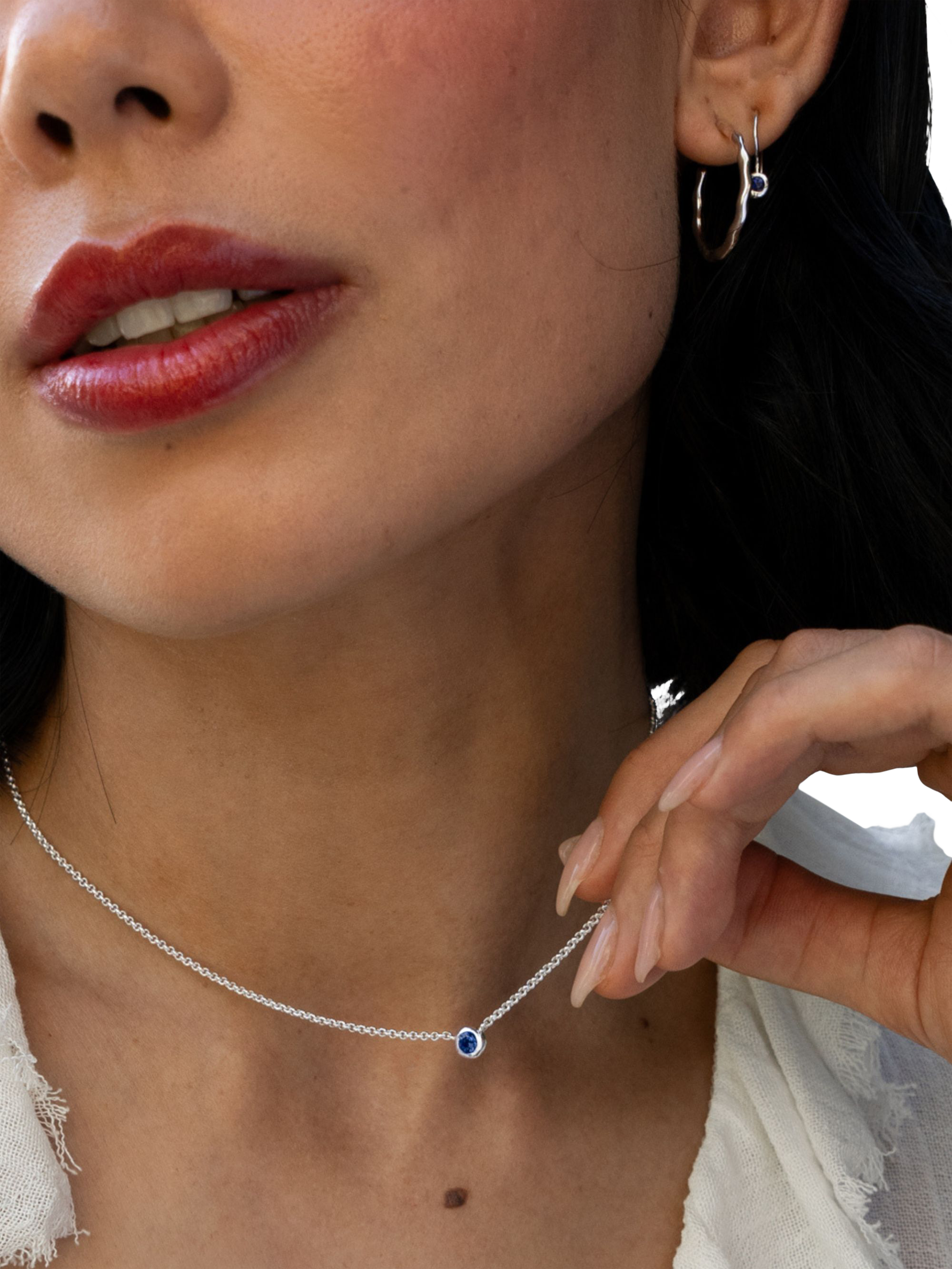 close up of a model holding a pendant necklace