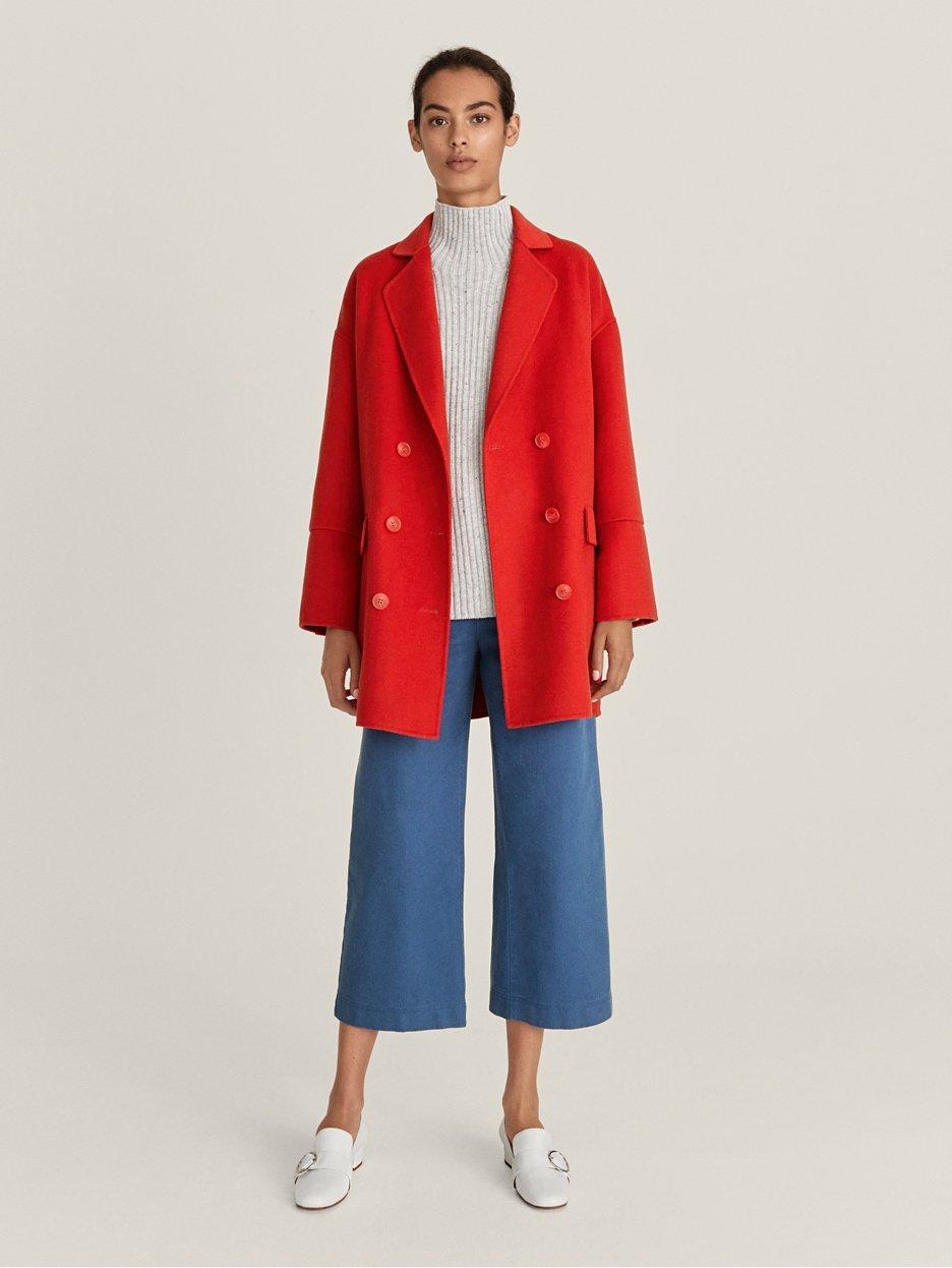 Model wearing red coat and blue wide-leg cropped trousers