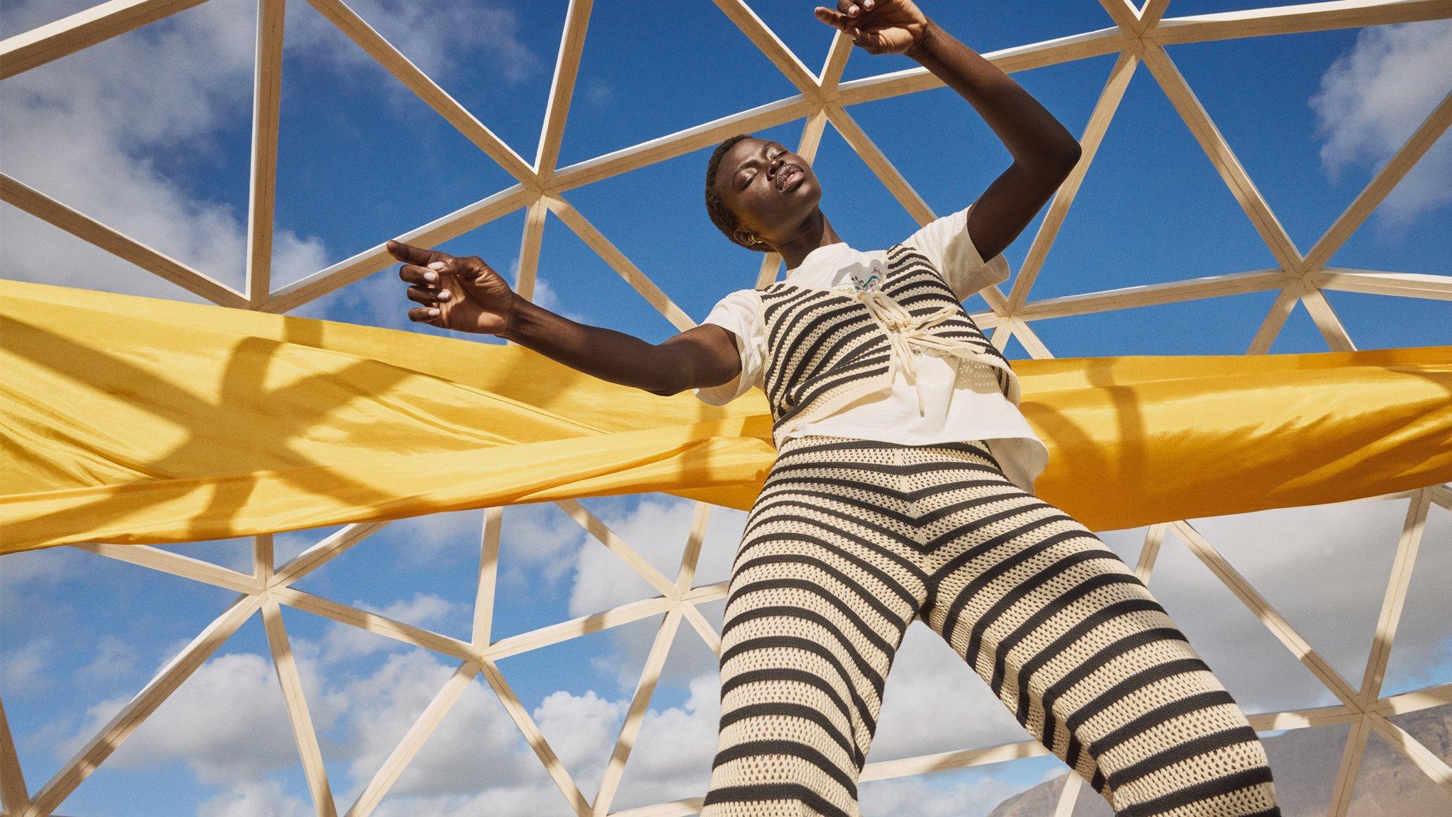 Image of a model with yellow flag behind her wearing stripy two piece
